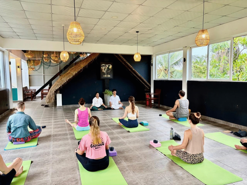Experienced yoga instructors guiding students through asana practice during a yoga teacher training course.